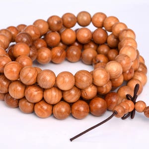 May include: A strand of brown wooden beads with a brown string tied at the end. The beads are round and have a smooth, polished finish.