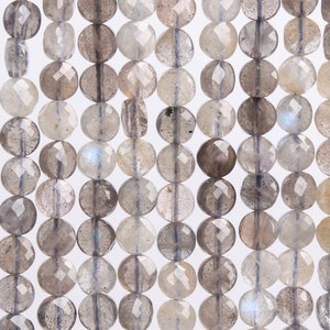 Peut inclure: Gros plan sur un fil de perles de labradorite. Les perles rondes et facettées sont de couleurs grises, beiges et blanches. Chaque perle mesure environ 8 mm de diamètre. Les perles ont un éclat irisé et sont enfilées.