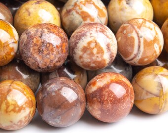 May include: Close-up of a strand of round, polished, brown, yellow, and white agate beads. The beads have a marbled pattern and a glossy finish.