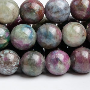 Pode incluir: Close-up de um fio de contas redondas multicoloridas. As contas são uma mistura de verde, rosa e branco com um acabamento brilhante.