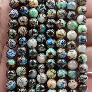 K&ouml;nnte beinhalten: Eine Kette aus blauen, gr&uuml;nen und braunen Edelsteinperlen. Die Perlen sind rund und haben ein geflecktes Muster.