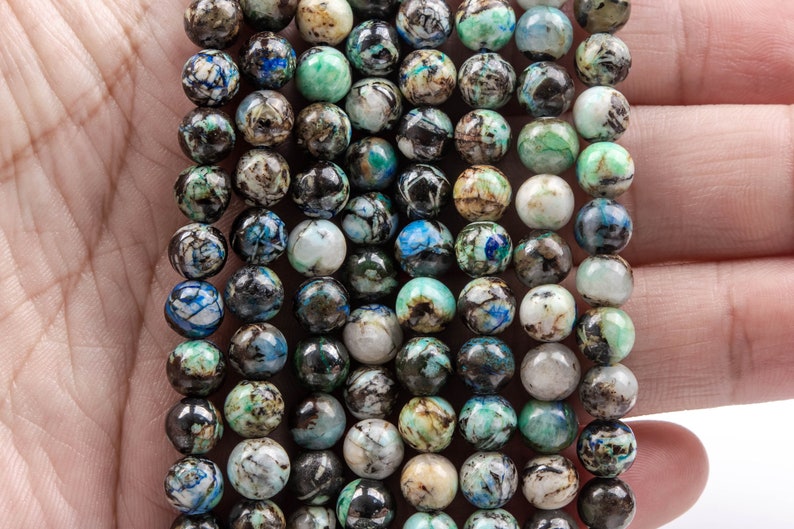 K&ouml;nnte beinhalten: Eine Kette aus blauen, gr&uuml;nen und braunen Edelsteinperlen. Die Perlen sind rund und haben ein geflecktes Muster.