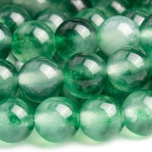 May include: A strand of round, green jade beads. The beads are translucent and have a slight shimmer.