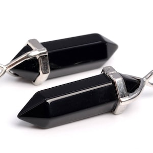 May include: Two black onyx crystal point pendants with silver-toned metal bail loops. The pendants are faceted and have a pointed tip.
