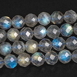 May include: A strand of faceted labradorite beads, each bead is a light blue, white, and grey colour with iridescent flashes of colour.
