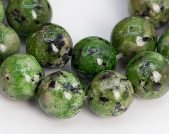May include: A strand of green and black speckled round beads. The beads are made of natural stone and have a polished finish.