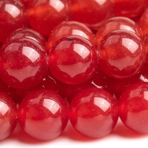 Könnte beinhalten: Eine Reihe roter Edelsteinperlen. Die Perlen sind rund und glatt, mit einem glänzenden Finish.