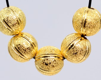 May include: A gold necklace with five round, textured beads. Each bead has a grooved design.