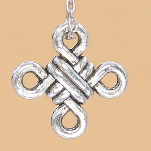 May include: Silver charm with a knot design in the shape of a cross.