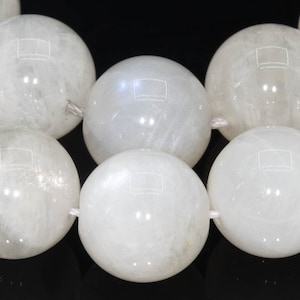 May include: A strand of white moonstone beads, each bead is round and smooth. The beads are strung on a white thread.