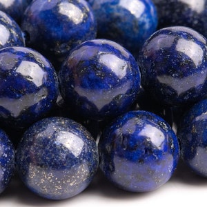 May include: A close-up of a strand of round, dark blue lapis lazuli beads with gold flecks. The beads are smooth and polished.