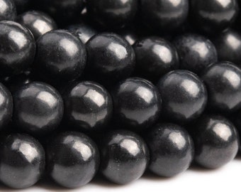 May include: A close-up of a strand of black round beads. The beads are smooth and shiny, and they are arranged in a random pattern.