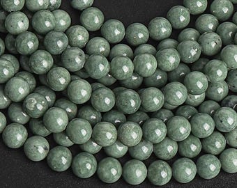 May include: A close-up of a strand of round, green jade beads. The beads are smooth and polished, and they have a natural, earthy look.