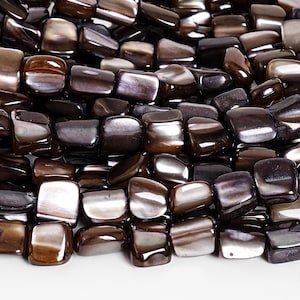 May include: Close-up of a collection of polished, square-shaped beads. The beads have a lustrous, iridescent quality with a color palette of deep browns, blacks, and hints of silver. The beads are likely for jewelry making.