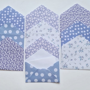 May include: A set of six decorative envelopes with different patterns in shades of blue and white. The envelopes are arranged in three stacks of two, with the top envelope of each stack folded open to reveal a blank white envelope inside.