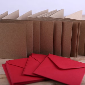May include: A stack of brown blank cards with red envelopes. The cards are folded in half and the envelopes are stacked on top of each other.