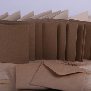 May include: A stack of brown blank greeting cards with matching brown envelopes. The cards are folded in half and have a rough texture.