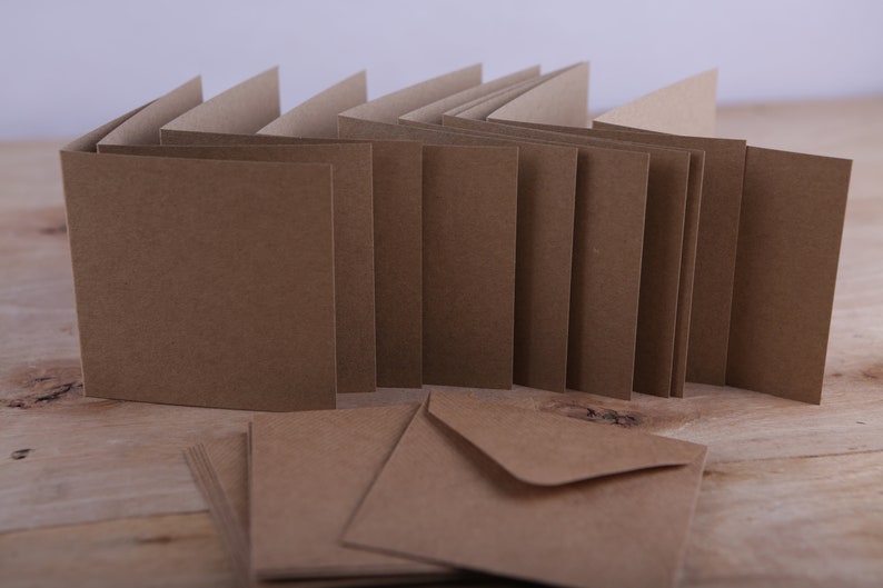 May include: A stack of brown blank greeting cards with matching brown envelopes. The cards are folded in half and have a rough texture.