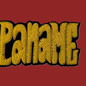 Può includere: Una toppa ricamata in oro con la parola "PANACHE" in un carattere stilizzato.