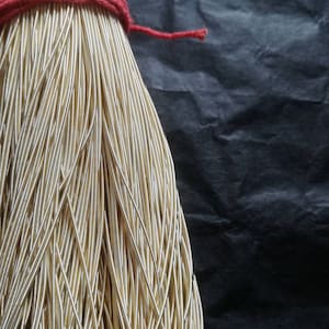 Könnte beinhalten: Ein Bündel goldfarbener Gummikordel, gebunden mit einer roten Schnur. Die Kordel ist in einem ordentlichen, organisierten Stapel angeordnet.