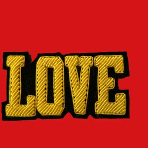 Peut inclure: Un patch brodé noir et or avec le mot "LOVE" en grandes lettres audacieuses.