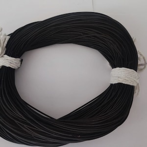 May include: A spool of black cord tied with white string. The cord is wound tightly and is ready to be used for crafting or other projects.