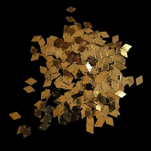 Peut inclure: Un tas de paillettes dorées en forme de diamant, éparpillées sur un fond noir.