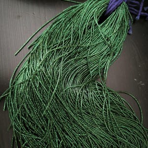 Peut inclure: Un grand paquet de perles de rocaille métalliques vertes. Les perles sont très petites et ont une finition brillante.