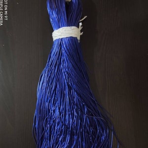 Peut inclure: Un paquet de cordon bleu foncé, noué avec une ficelle blanche, sur un fond de bois foncé.