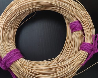 May include: A spool of gold-colored wire wrapped with purple fabric ties. The wire is wound tightly in a circle.