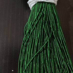 Op de afbeelding: Een bundel groene, metalen kralenkoord, gebonden met een wit touwtje.