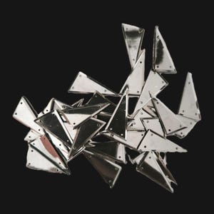 Pode incluir: Um conjunto de triângulos metálicos prateados brilhantes com pequenos orifícios, sobre um fundo preto. Os triângulos têm uma superfície refletora, criando reflexos e sombras.