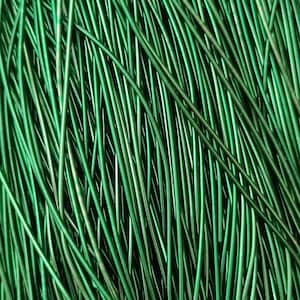 May include: A close-up of a bundle of green, metallic, flexible cords. The cords are arranged in a random pattern, creating a textured background.