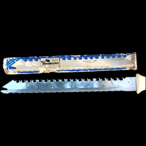 May include: A stainless steel serrated knife with a white handle and a specialized fork tip, accompanied by its original blue and white cardboard packaging. The packaging features the text Quikut Inc. Stainless U.S.A. and a graphic illustration.