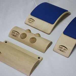 May include: Four wooden back support tools with the brand name "Sae arc" printed on each. Two of the tools have a blue foam pad on top. One tool has three wooden balls attached to the top.
