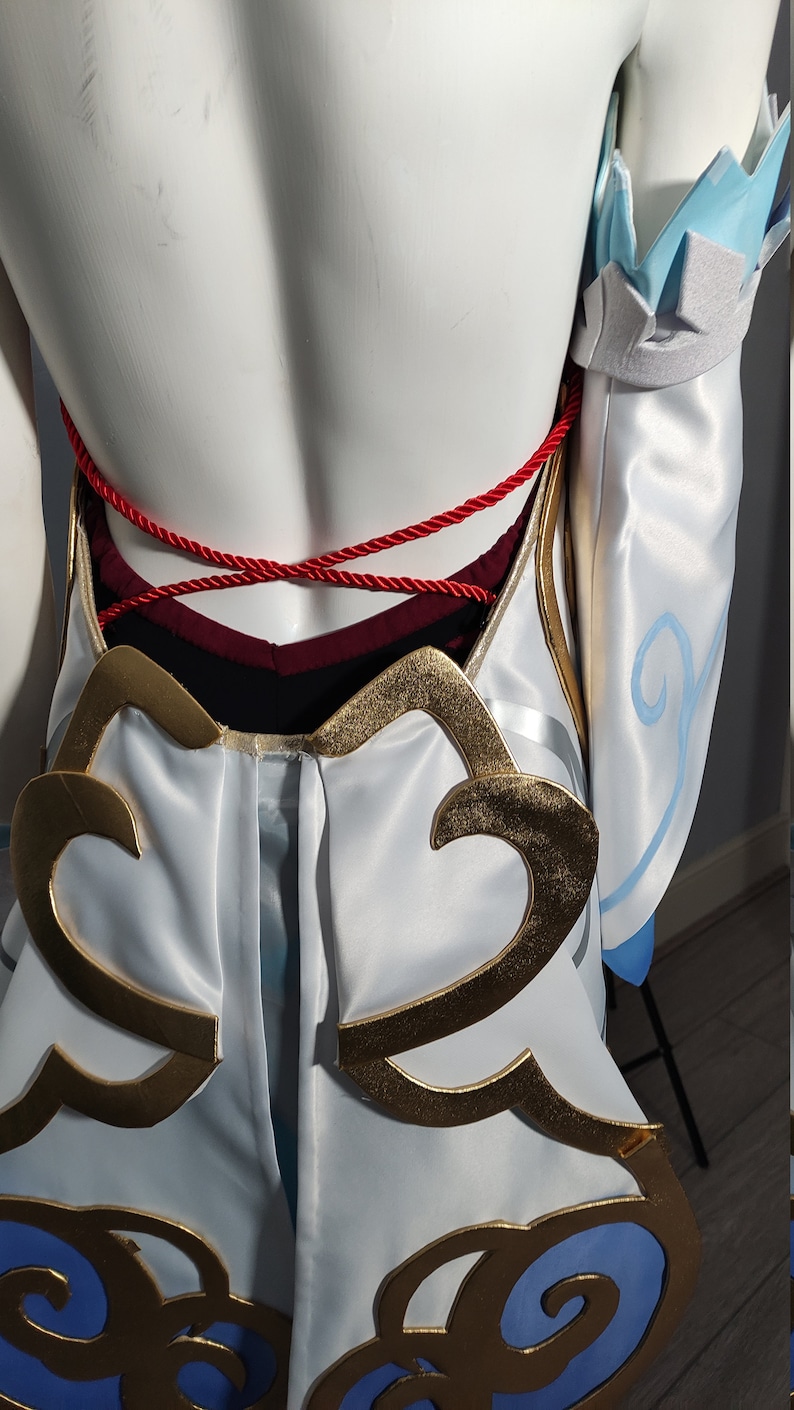 May include: White and blue costume with gold and blue cloud designs. The costume has a red rope tied around the waist.