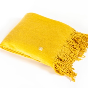Peut inclure: Une couverture jaune avec une bordure en franges. La couverture est pliée en deux et porte une petite étiquette dans le coin.