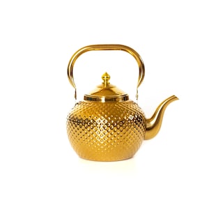 May include: A gold-colored stainless steel kettle with a textured surface and a matching lid. The kettle has a curved handle and a spout.