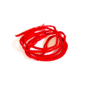 Könnte beinhalten: Nahaufnahme eines Stapels roter Schnurarmbänder. Die Armbänder sind geflochten und verknotet.