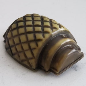 Puede incluir: Una pequeña figura de plástico beige y marrón de una tortuga con un caparazón estampado.