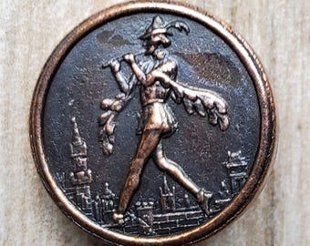 Botón metálico vintage de los años 30 con la imagen del Flautista de Hamelín.