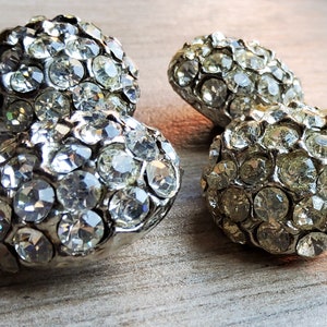 May include: Four silver-toned, round, decorative buttons covered in clear rhinestones.
