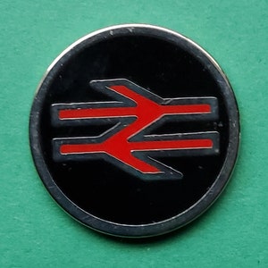 Op de afbeelding: Een zwarte en rode metalen pin met het British Rail-logo. Het logo is een gestileerde dubbele pijl met een rode omtrek.
