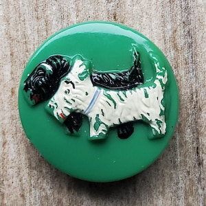 May include: A green button with a white and black dog illustration. The dog is wearing a blue collar.