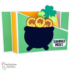 May include: A green and gold card with a black pot of gold and shamrocks. The card says "Shamrock Wishes".