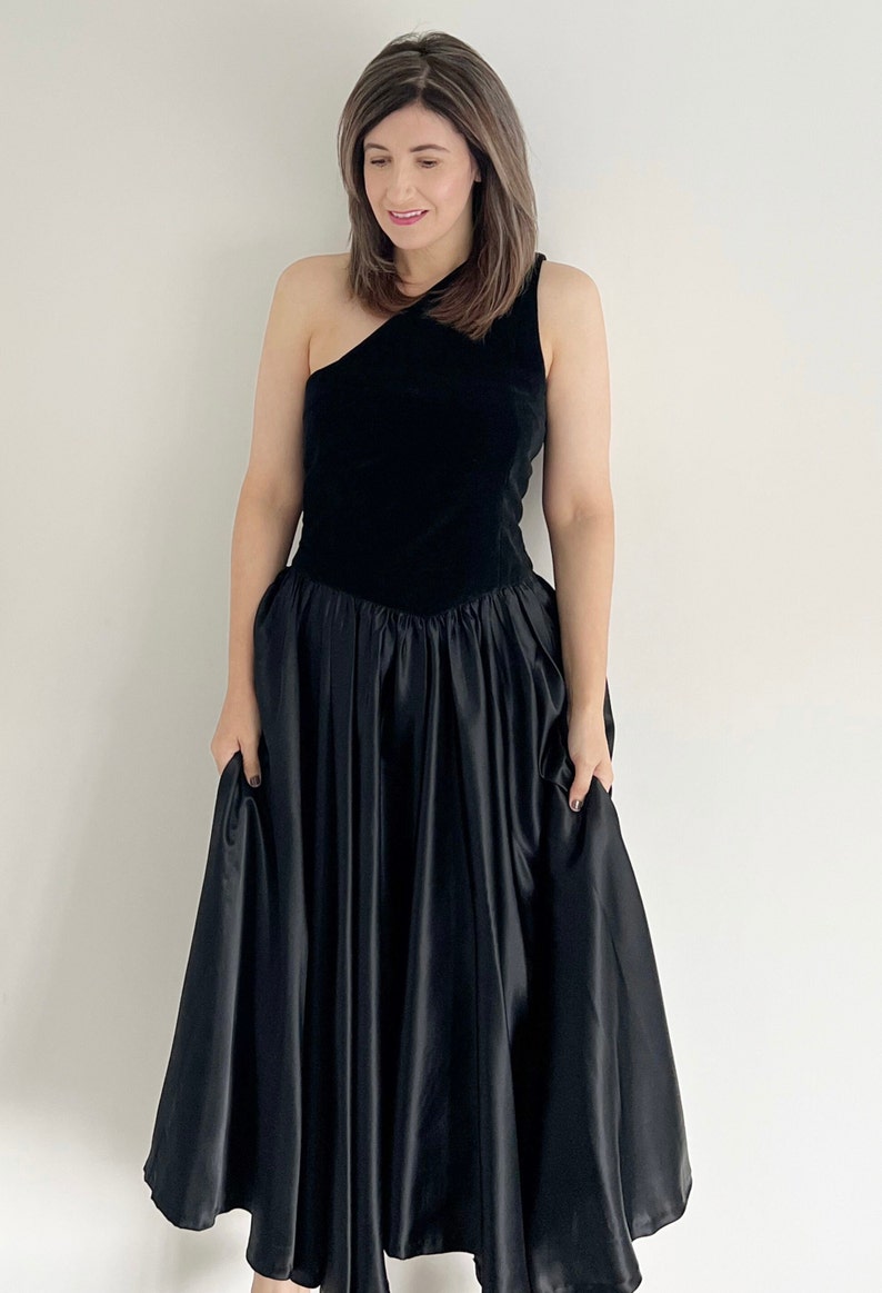 Vintage black full circle one shouldered prom dress. The bodice of the dress is velvet with a full skirt section of the dress.  The dress is mid calf and ideal for parties, occasions or the prom.  UK 12 14 today