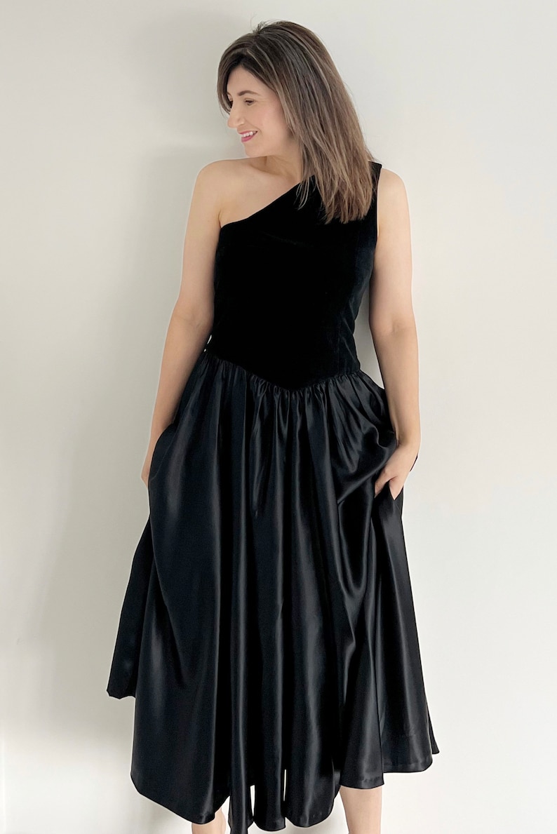 a beautiful vintage black handmade party dress.  The dress has one shoulder, it has a full circle skirt section and mid calf length.  Dress is a UK 12 14