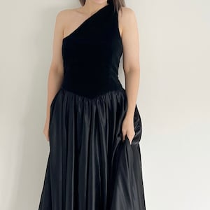 A black velvet occasion dress.  The dress dates from the 80s and has a velvet bodice with a full circle skirt section.  The dress has one shoulder and ideal for a UK 12 14