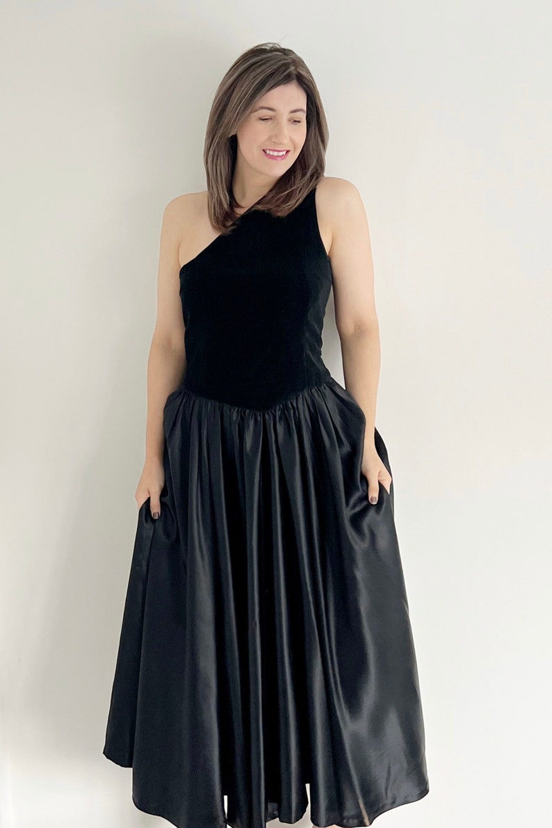 A handmade vintage black occasion 80s dress.  The dress features one shoulder and a slight V waist.  The dress has a full circle black skirt section.  A great vintage party dress. UK 12 14 today