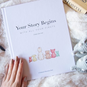May include: A white book with the title "Your Story Begins With All Your Firsts" and a baby's first book subtitle. The book cover features a watercolor illustration of a group of animals, including a cat, a dog, and a rabbit.